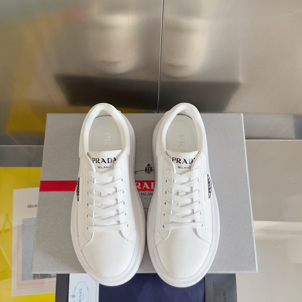 Pair of unisex white sneakers with PRADA logo on the tongue and heel