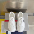 Pair of unisex white sneakers with PRADA logo on the tongue and heel