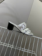 Silver slide sandal with stacked buckles and black block heel, profile view