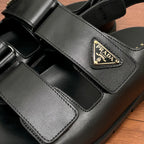 Prada unisex black sandal strap close-up with triangular logo patch and stitched details