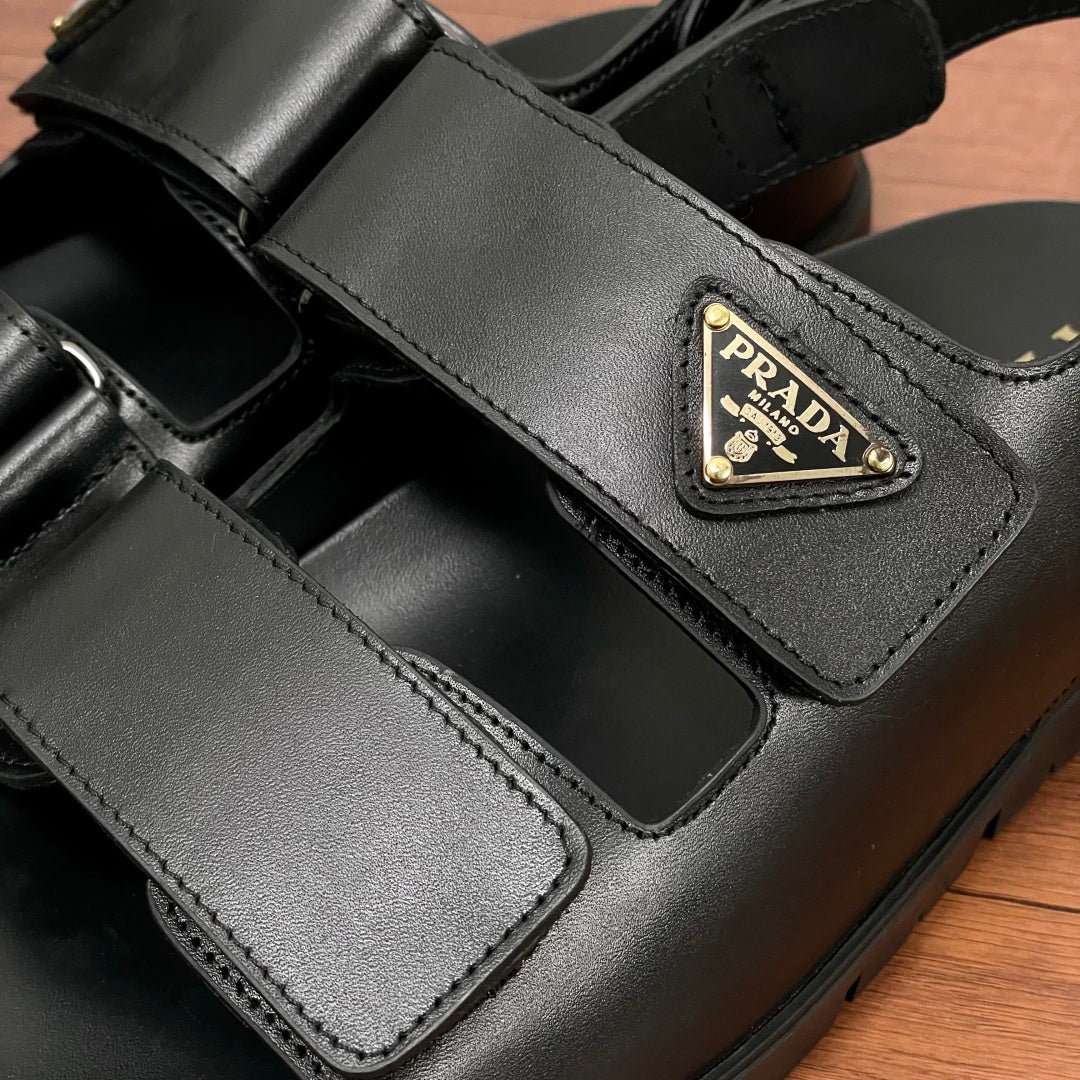 Prada unisex black sandal strap close-up with triangular logo patch and stitched details