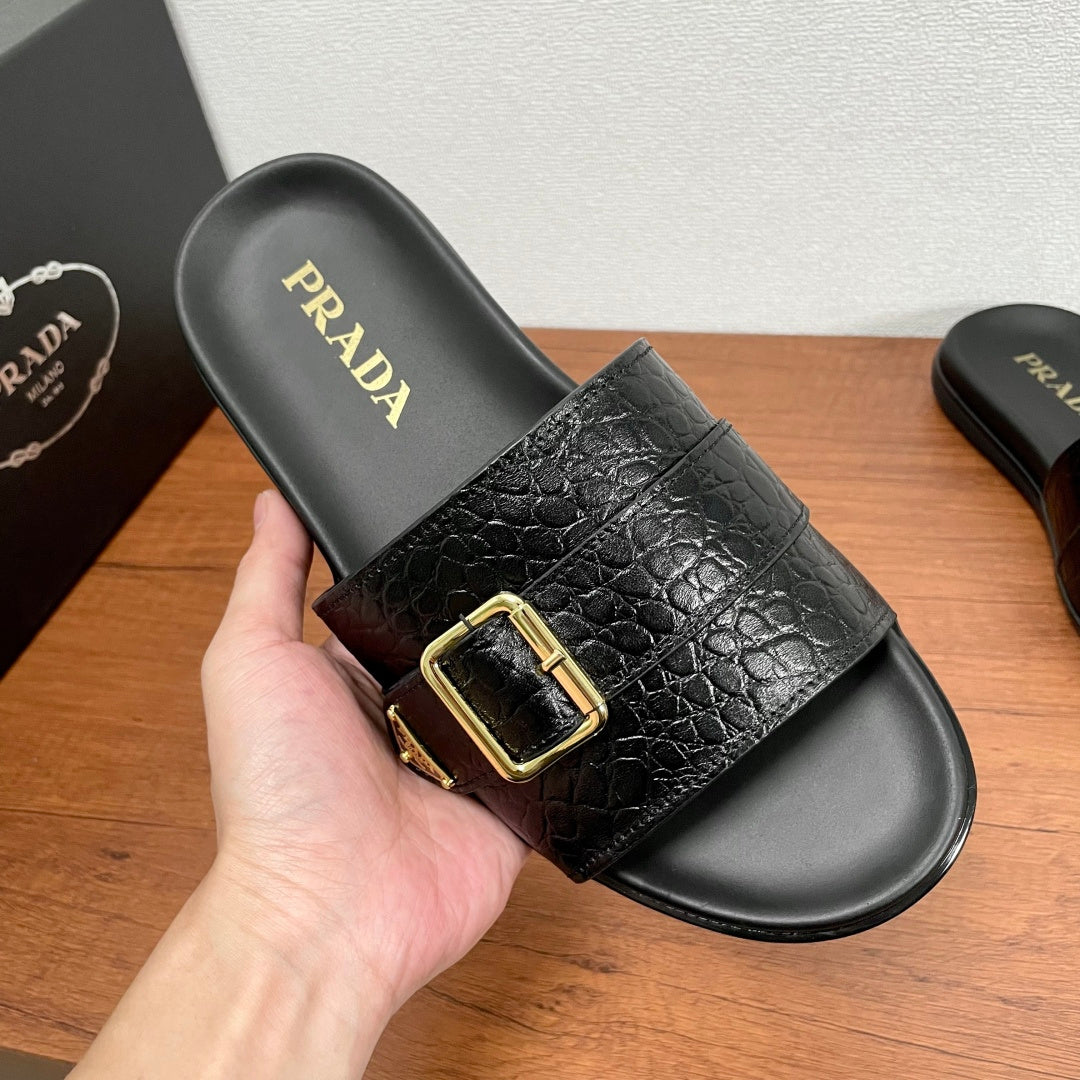 Prada black slide sandal with gold buckle strap and logo footbed