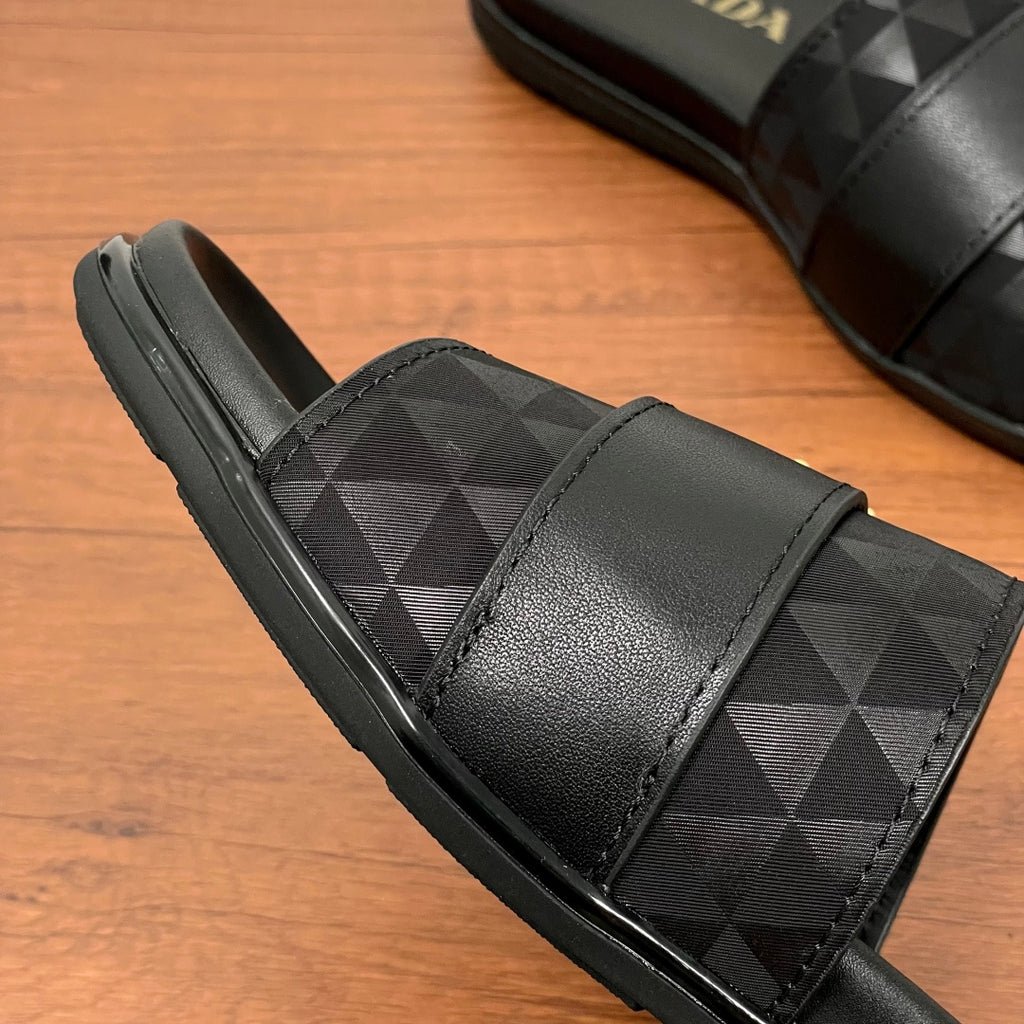 Black Prada slide sandal with geometric strap and cushioned insole, side view.