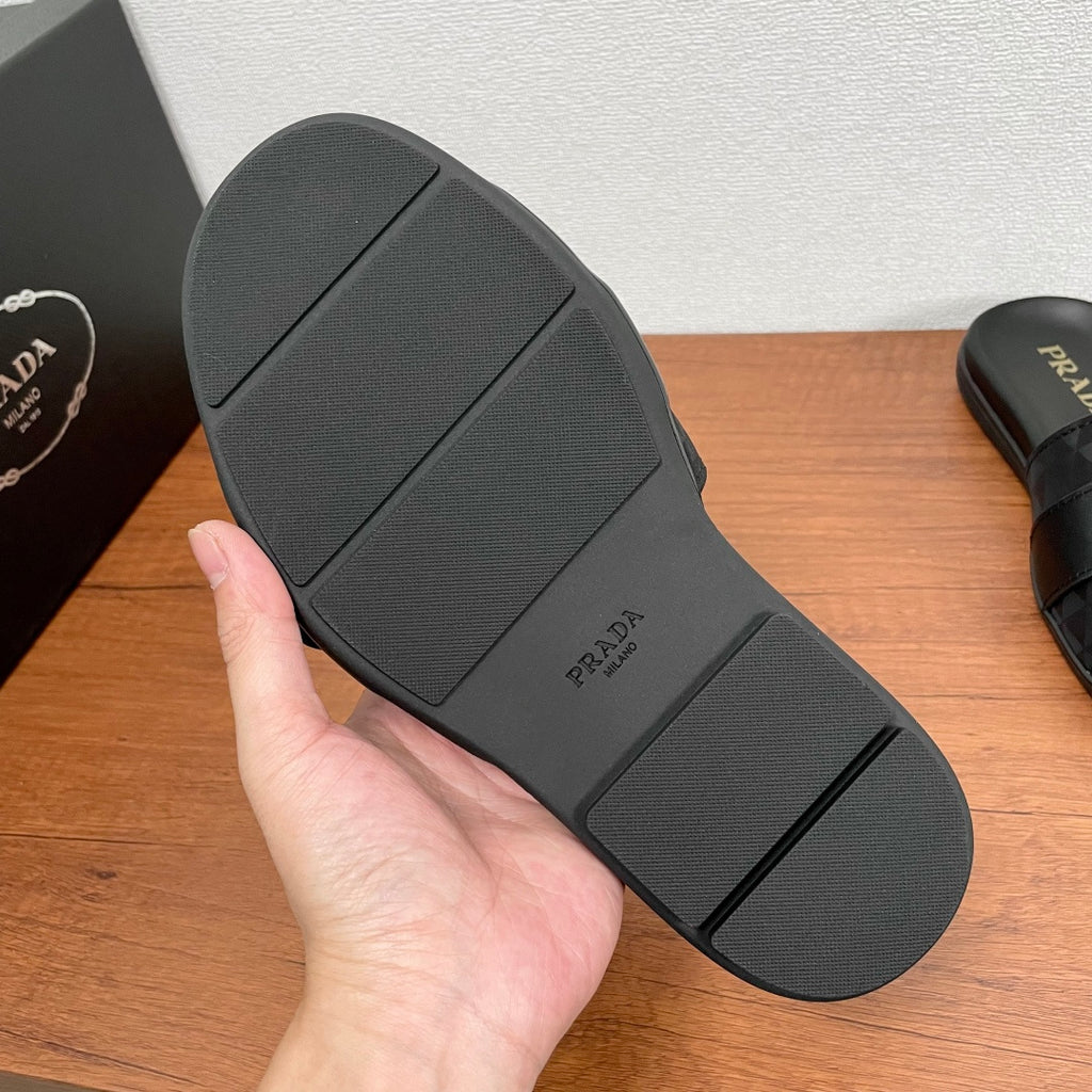 Black Prada slide sandal outsole with tread and PRADA logo, flat sole.