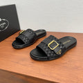 Black Prada slide sandals with geometric patterned straps and gold buckle.