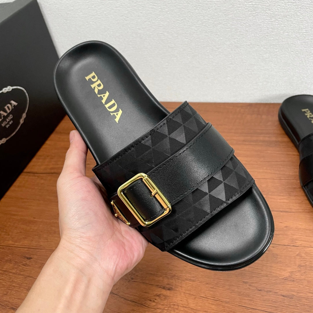 Black Prada slide sandal with geometric strap, gold buckle, leather-style footbed.