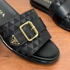 Black Prada slide sandal with geometric strap and gold square buckle, close-up.