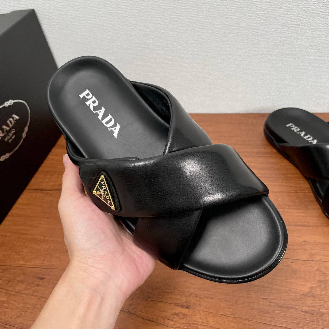 Black slide sandal with PRADA logo on footbed and gold logo patch on strap