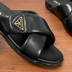 Close-up of black slide sandal upper with gold Prada logo plaque