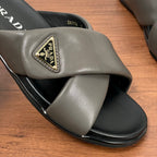Gray Prada slide sandal strap with gold triangle logo patch on leather