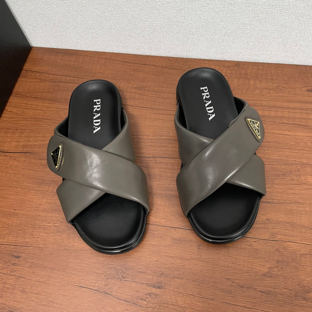 Gray Prada slide sandals with PRADA logo on black footbed, cross strap