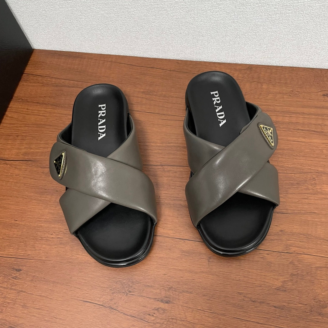Gray Prada slide sandals with PRADA logo on black footbed, cross strap