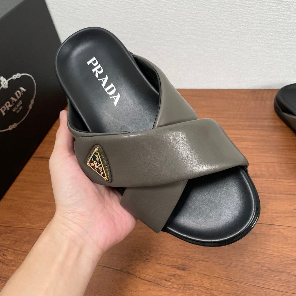 Gray Prada slide sandal in hand, PRADA logo on footbed and gold patch