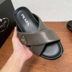Gray Prada slide sandal in hand, PRADA logo on footbed and gold patch
