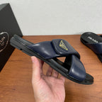 Prada navy slide sandal held in hand, wide strap with gold logo patch