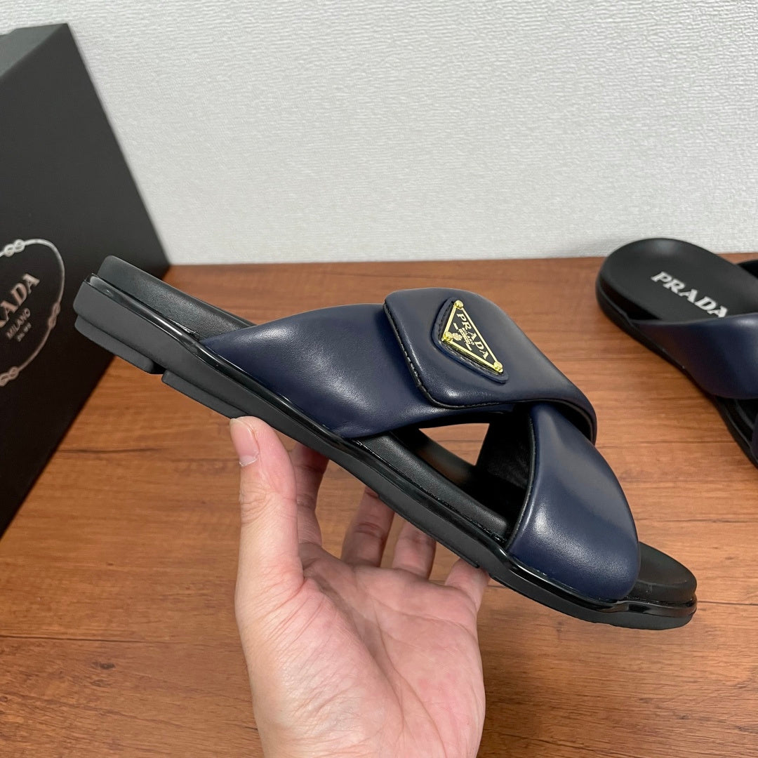 Prada navy slide sandal held in hand, wide strap with gold logo patch