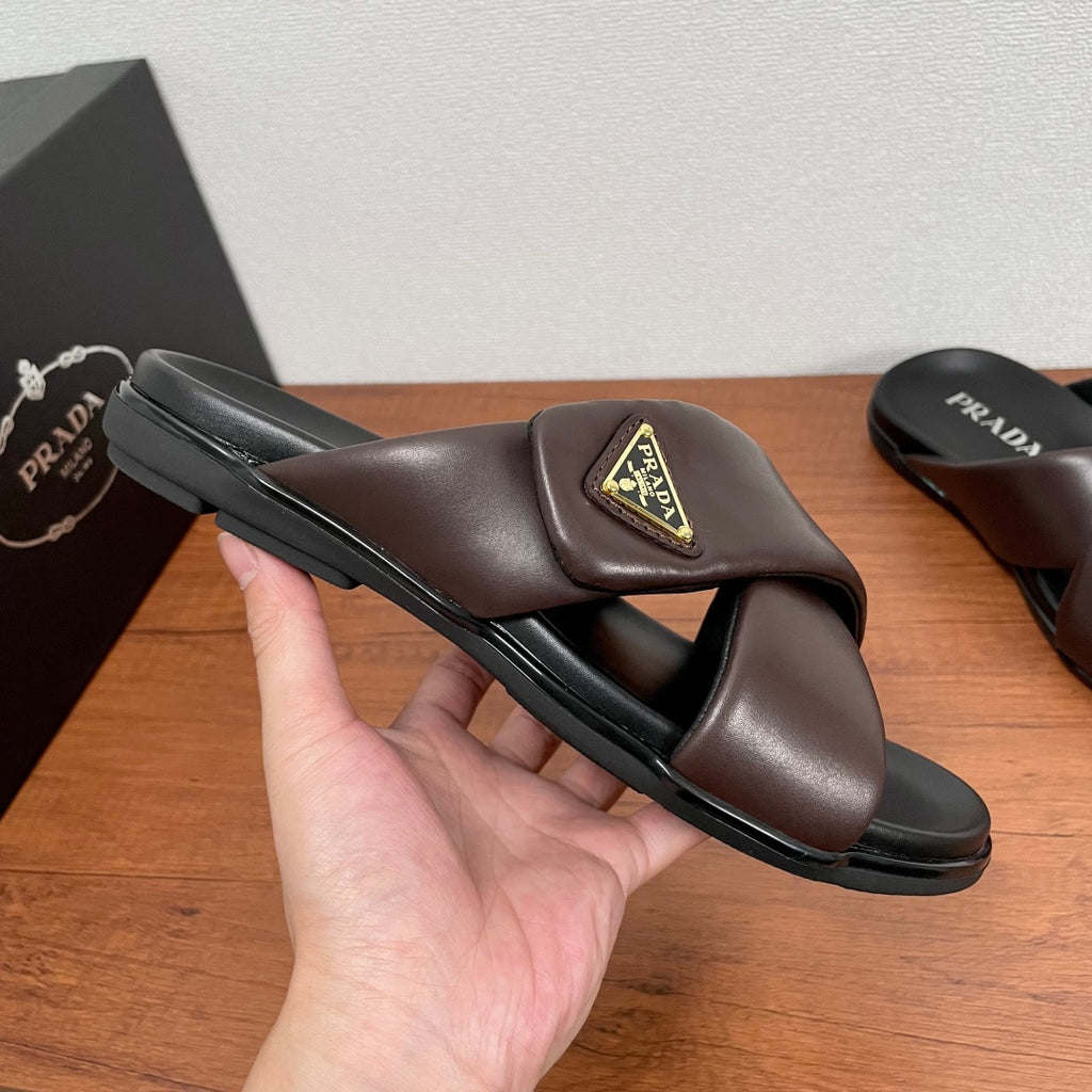 Dark brown slide sandals with gold triangular logo patch and cushioned black sole