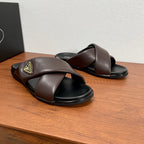 Dark brown slide sandals with X-style straps, black footbeds, and gold logo patch