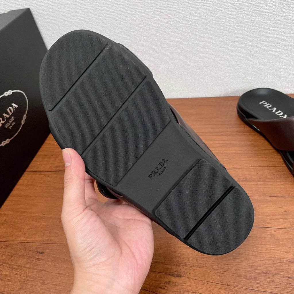 Dark brown slide sandal outsole with textured rubber tread and PRADA branding