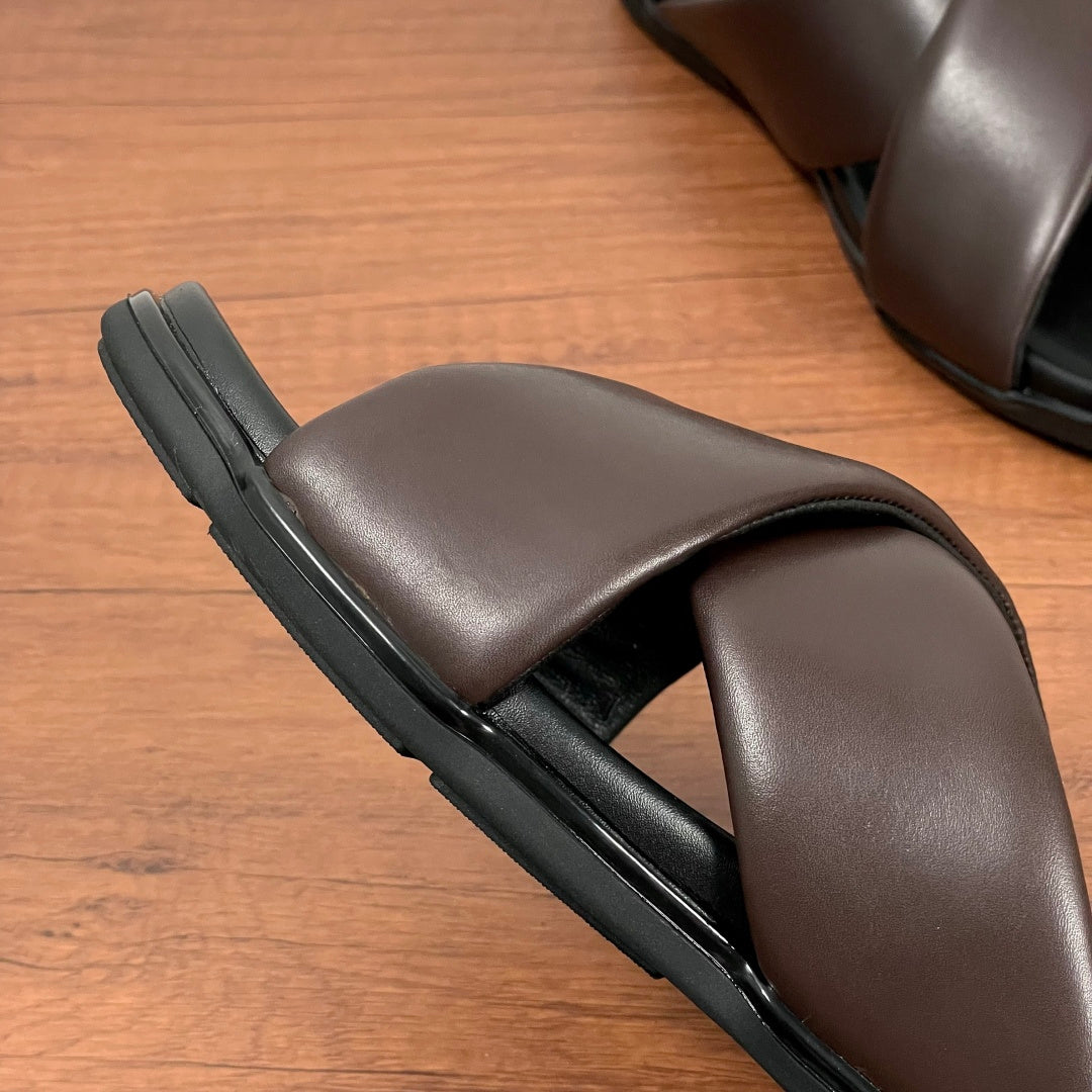 Dark brown slide sandal side view with thick black sole and smooth cross strap