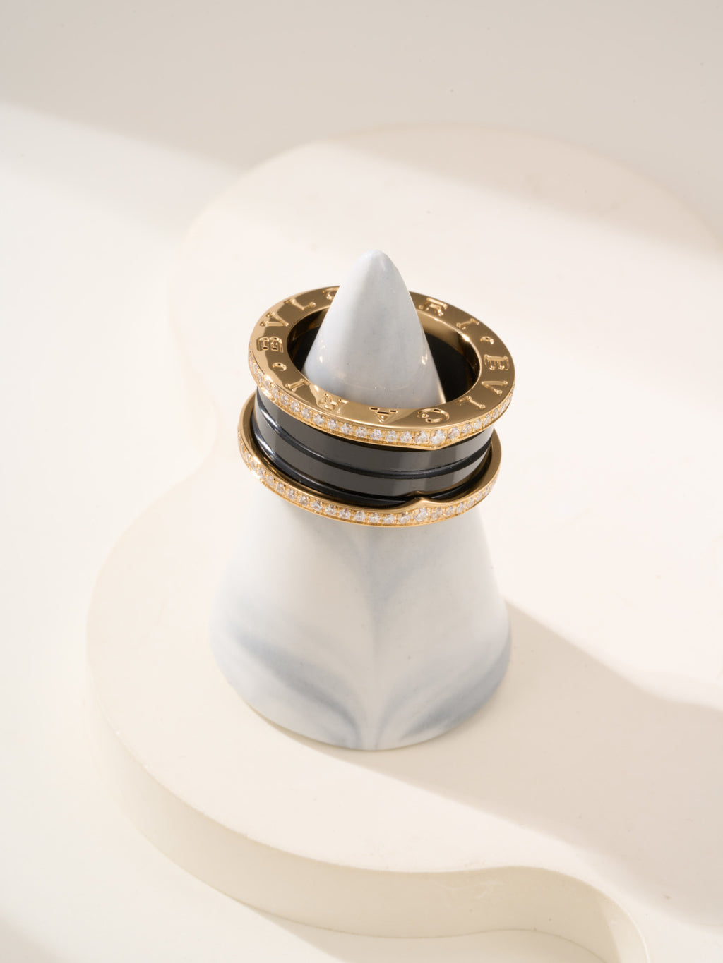 Gold-tone ring stack with black enamel band and pavé diamonds, top view