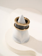 Gold-tone ring stack with black enamel band and pavé diamonds, top view