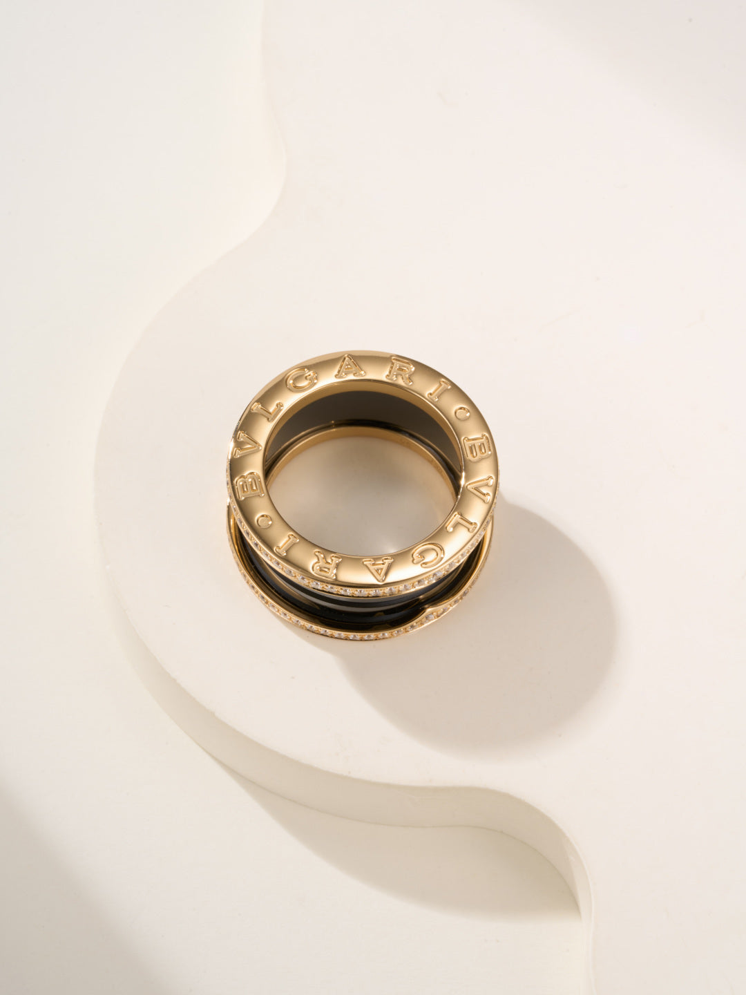 Gold-tone ring with engraved details and gemstone pavé edge, top view