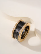 Gold-tone ring with black enamel band and pavé stones, close-up angle