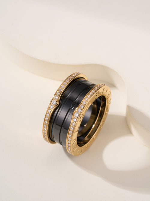 Gold-tone ring with black enamel band and pavé stones, close-up angle