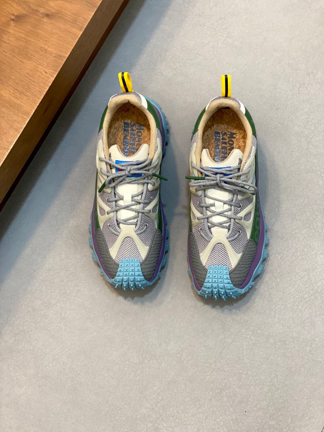 Moncler sneakers in light gray, purple, and blue with yellow pull tabs