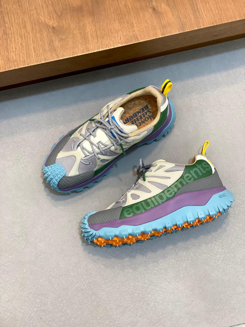 Moncler sneakers pair with gray uppers, green and purple accents, and blue sole