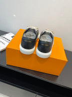 Louis Vuitton low-top sneakers with white rubber soles and dark uppers with charm details