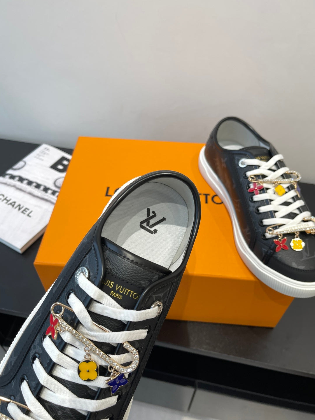 Louis Vuitton low-top sneaker with dark monogram, white laces, and decorative charm hardware