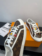 Louis Vuitton sneakers side view with brown monogram pattern, multicolor charm accents, white sole