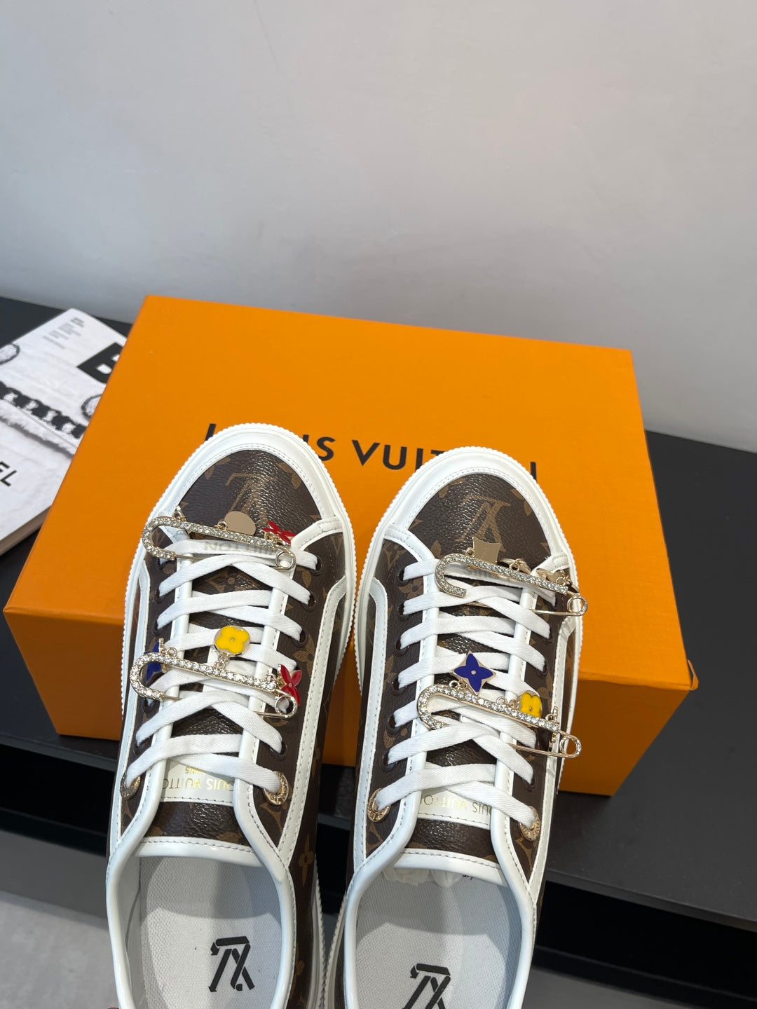 Louis Vuitton low-top sneakers with brown monogram uppers, white laces, and embellished charms
