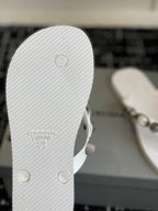 White rubber sole of thong sandal with circular rivets and embossed logo