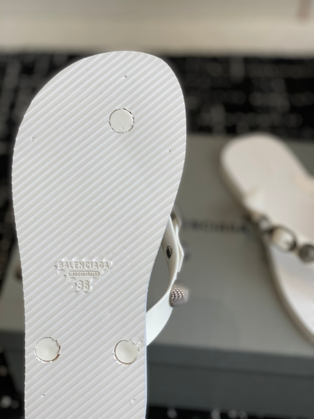 White rubber sole of thong sandal with circular rivets and embossed logo