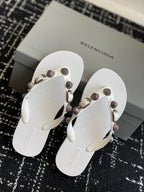 Pair of white thong sandals with circular stud straps and metal buckle