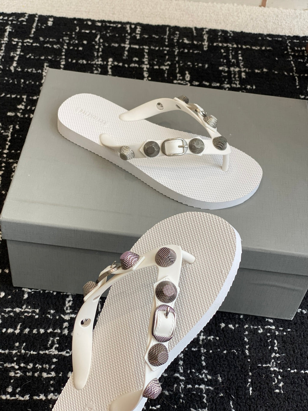 White thong sandals with studded strap and metal buckle, side angle