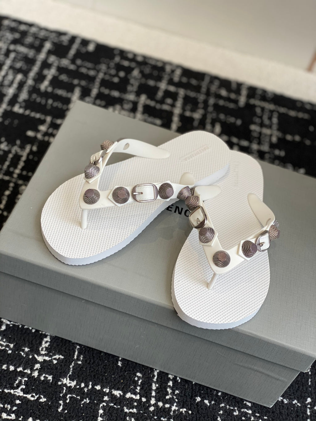 White thong sandals with metallic buckle and studded strap, front view