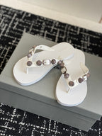 White thong sandals with metallic buckle and studded strap, front view