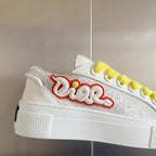 Unisex white sneaker with red-and-green script logo and bright yellow laces