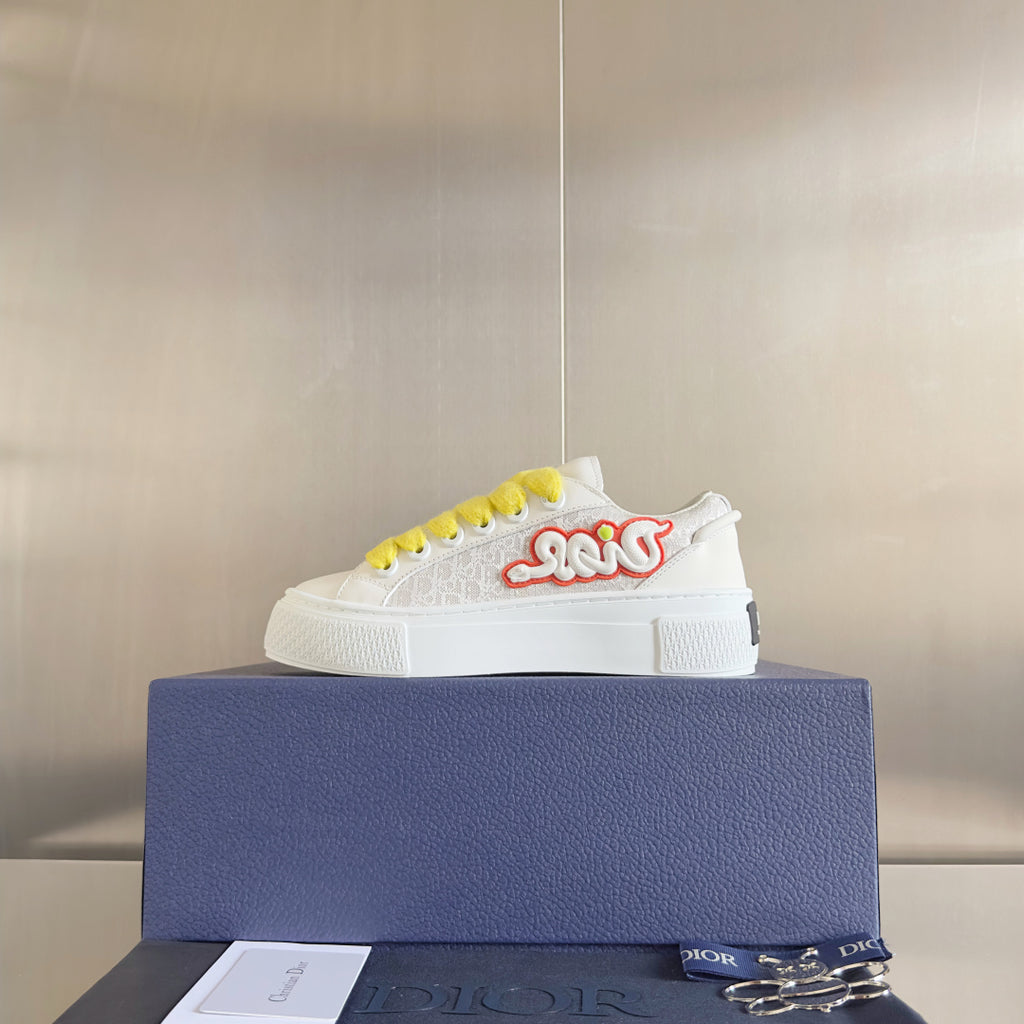 Unisex white platform sneakers with bright yellow laces and red script logo detail