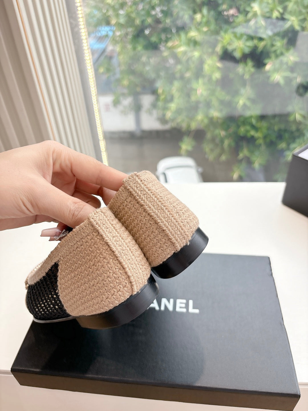 Chanel woven ballet flats held by hand, beige upper with black knit trim