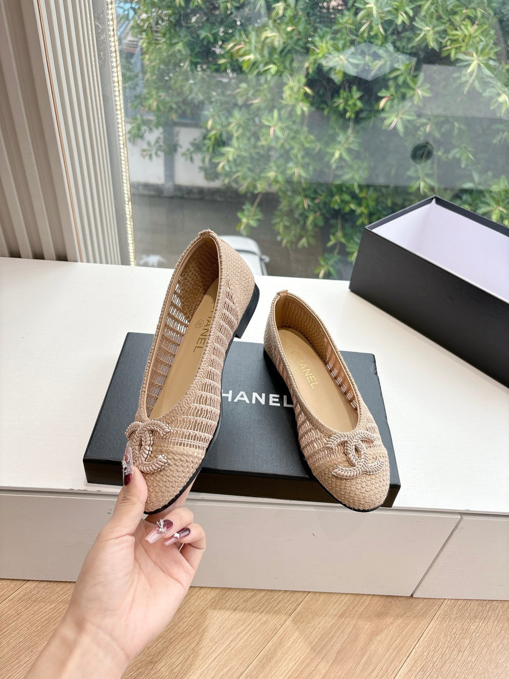 Beige woven ballet flats with braided bow detail; rubber sole visible and CHANEL text.