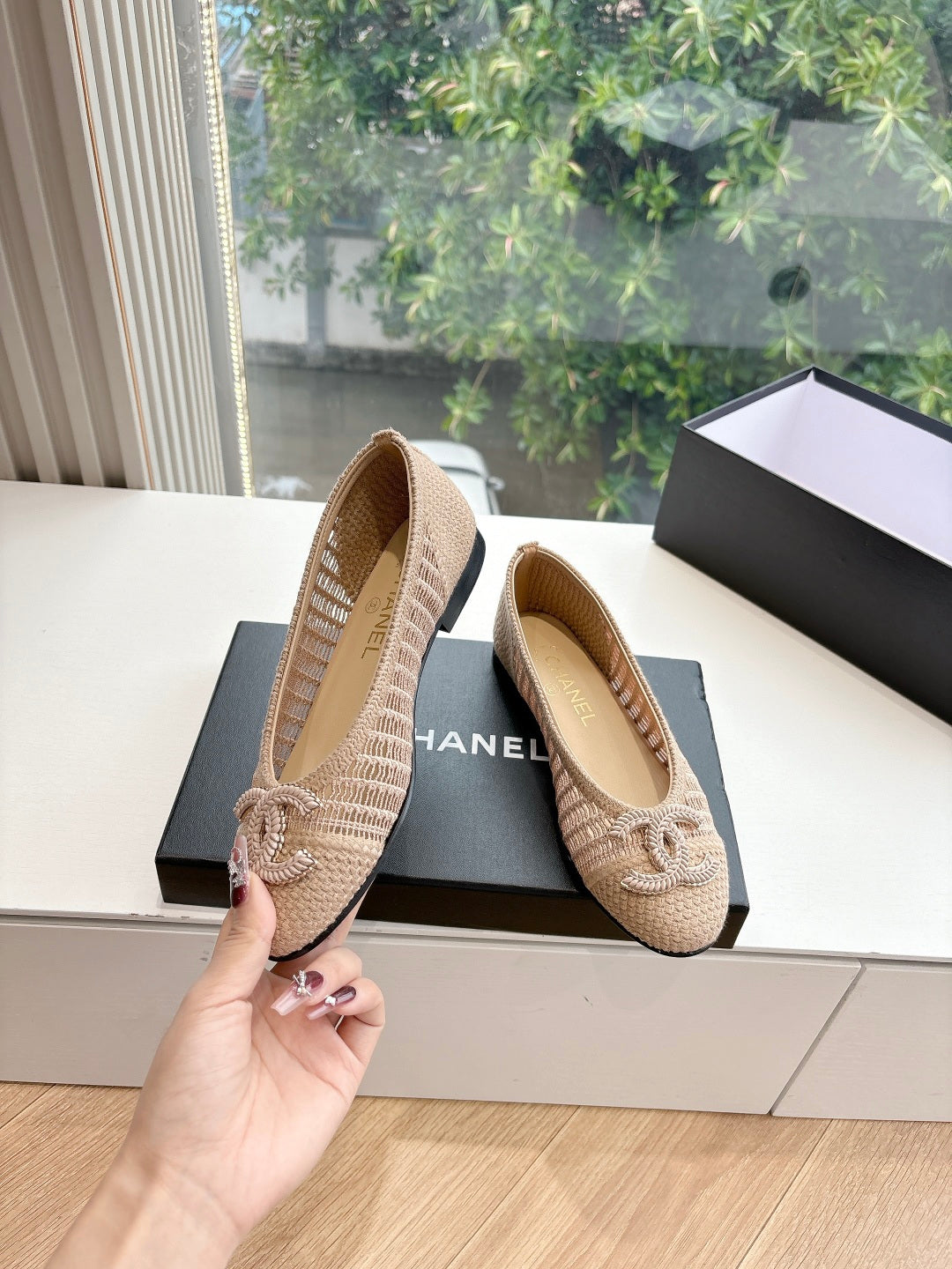 Beige woven ballet flats with braided bow detail; rubber sole visible and CHANEL text.
