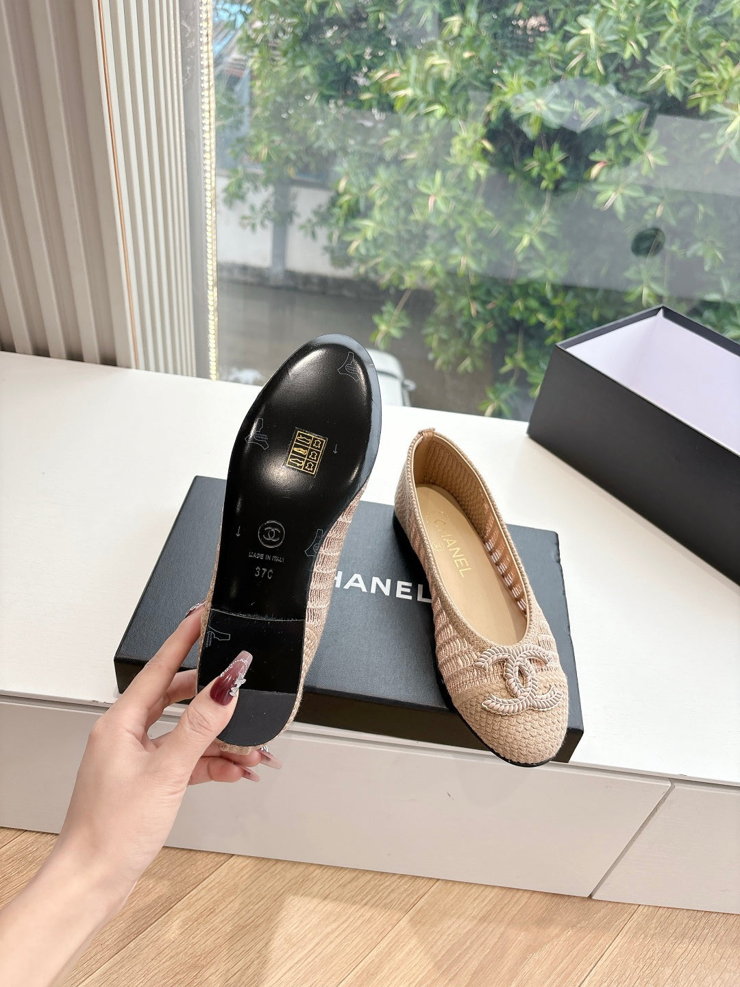 Beige woven ballet flat on box with braided bow detail, side angle.
