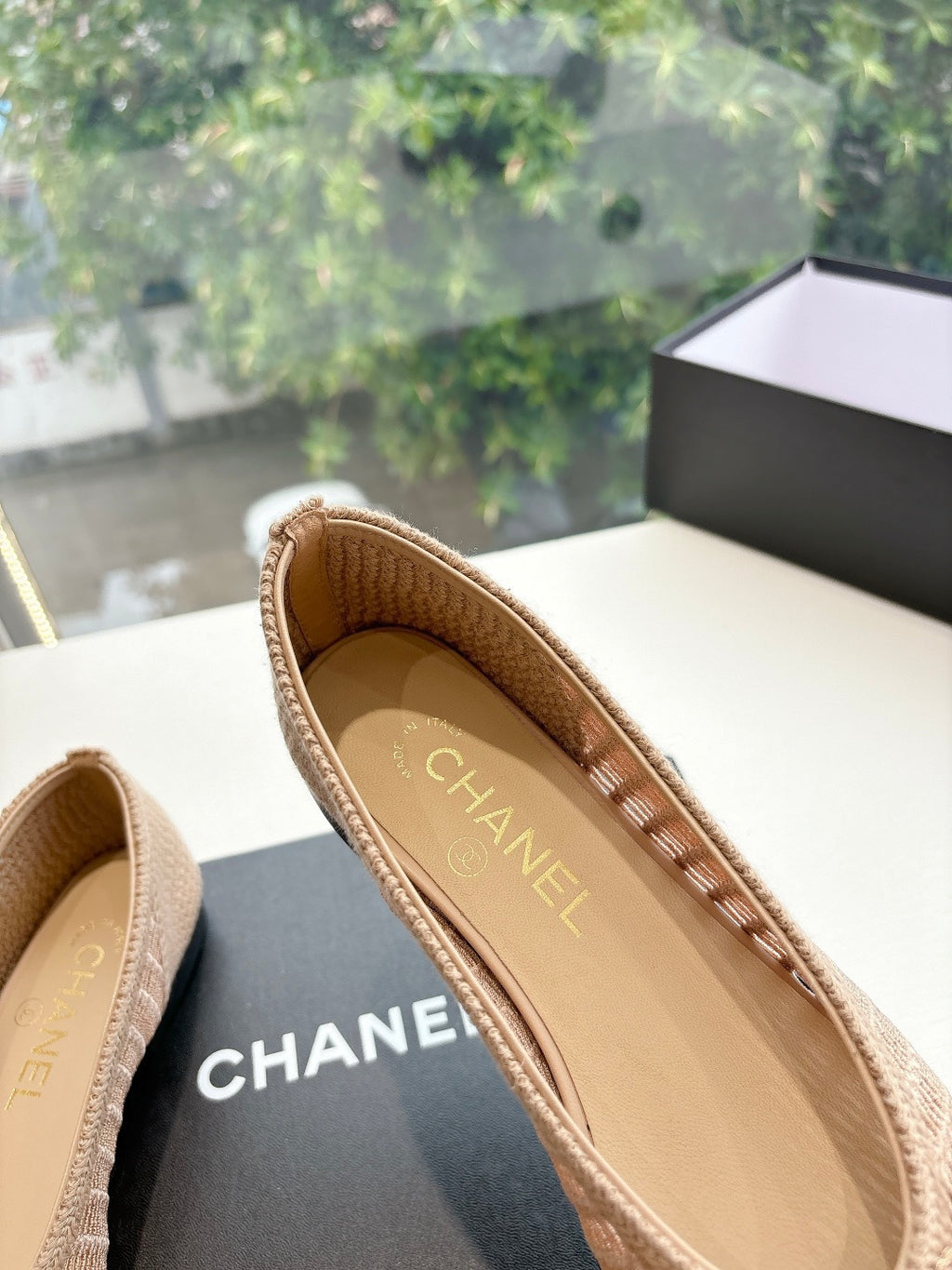 Beige woven ballet flats with CHANEL logo on insole, close-up of interior.