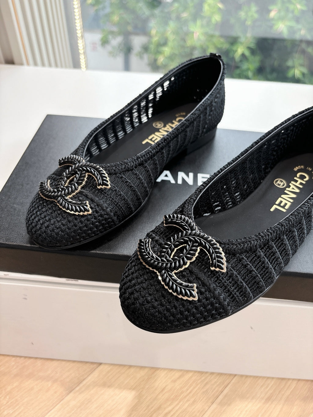 Close-up of black Chanel knit slip-on flats with CC-style bow logo embroidery