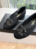 Close-up of black Chanel knit slip-on flats with CC-style bow logo embroidery